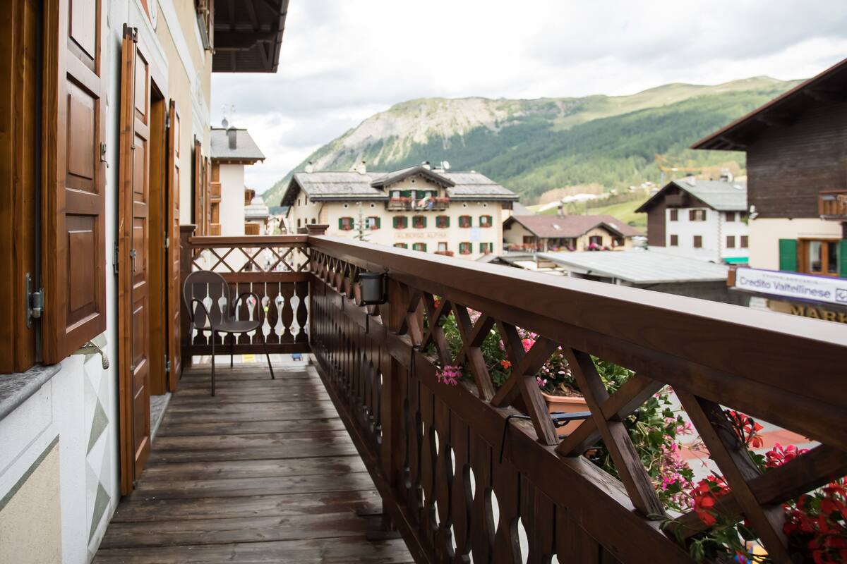 A wooden balcony with a view of traditional buildings and mountains in the background.