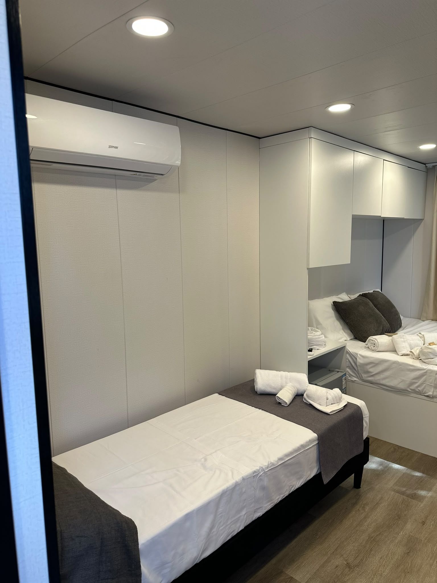 Ein kleines Hotelzimmer mit einem Einzelbett, einem Nachttisch und einem fest installierten Kleiderschrank.