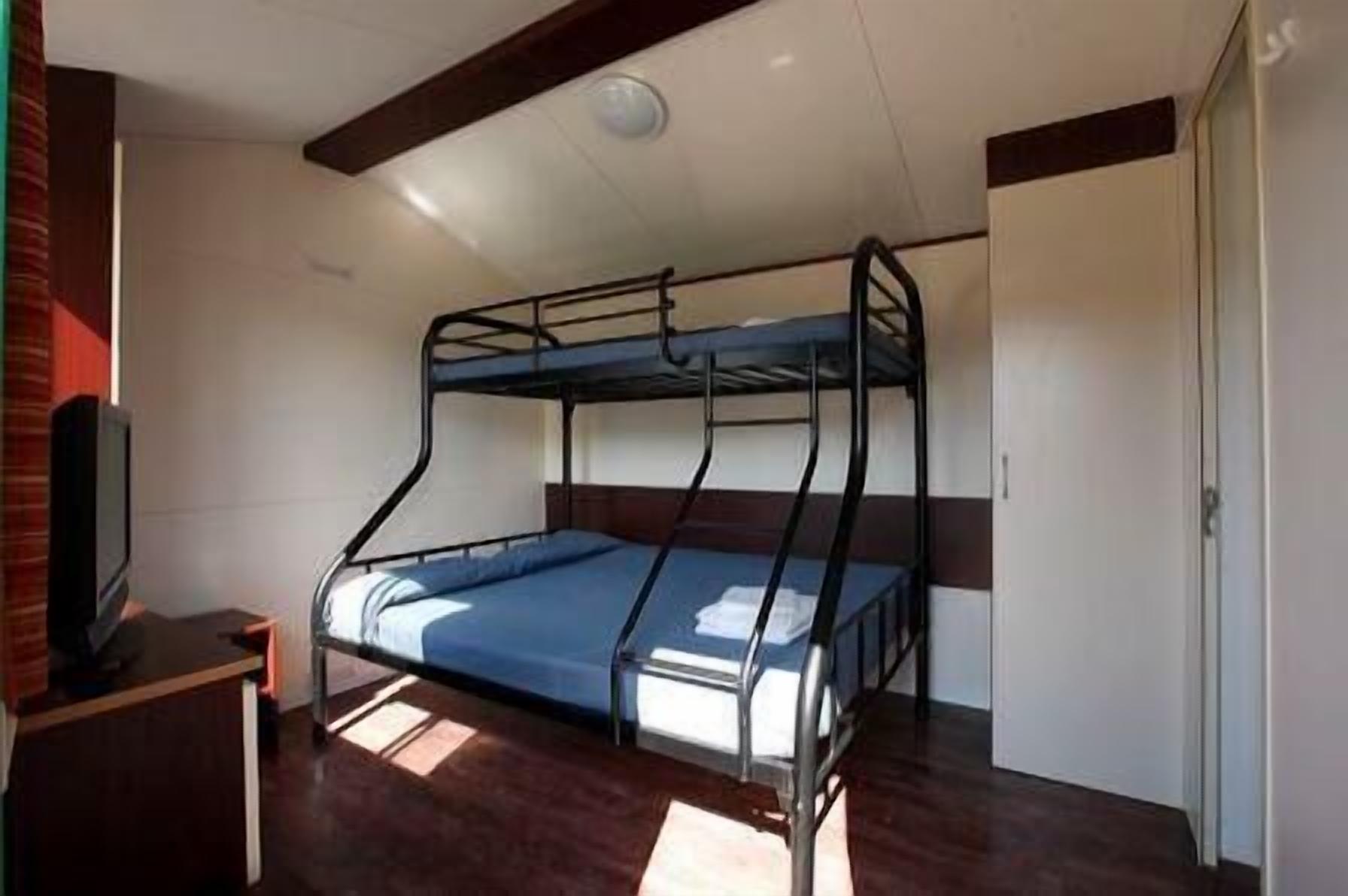 Habitación con literas, un televisor sobre una mesita, una puerta y una ventana.