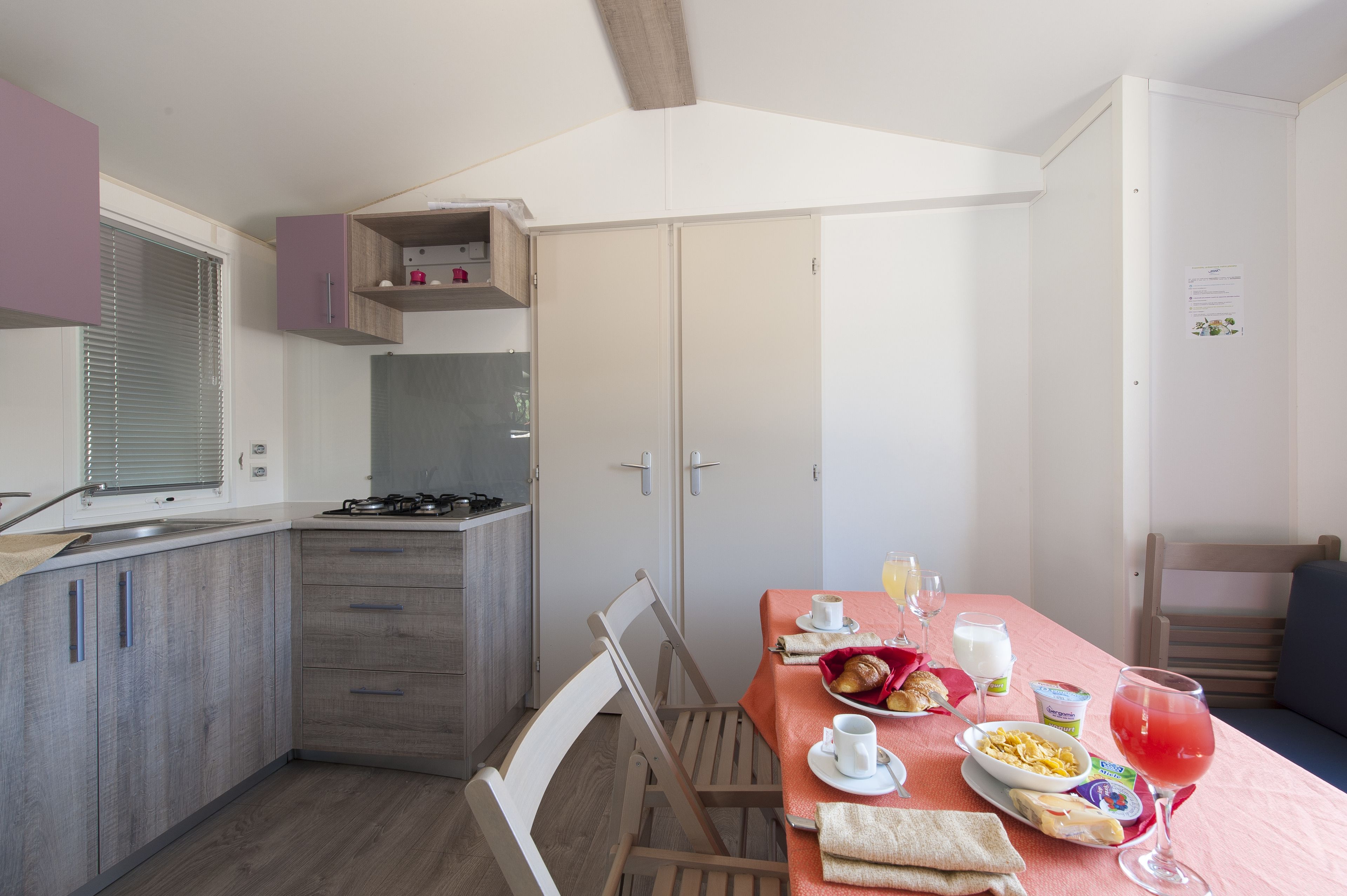 Une cuisine compacte avec un coin repas, comprenant une table dressée avec des aliments pour le petit-déjeuner et une boisson.