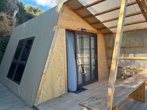 A small wooden cabin with a sliding glass door, a window, and a wooden deck. - Sporting Club Village (Mazara del Vallo)