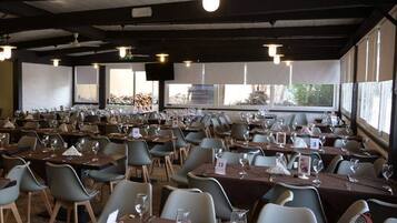 Une grande salle à manger avec des tables et des chaises, des places numérotées et une vue sur l’extérieur.