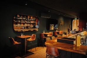 Un espace bar avec des tables et des chaises en bois, un comptoir et des étagères remplies de bouteilles et de verres.