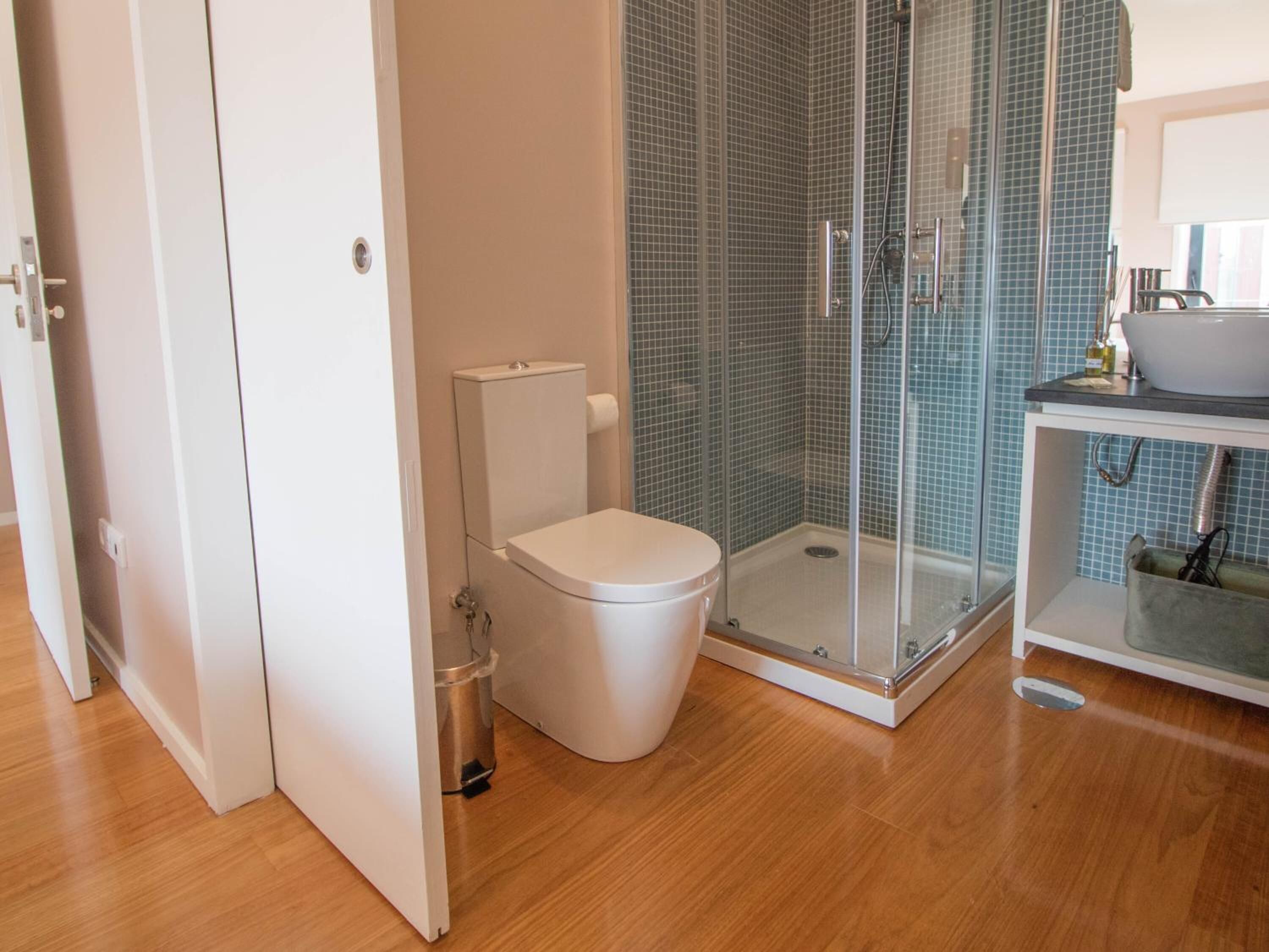Un baño con inodoro, cabina de ducha de vidrio y lavamanos.