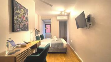 Habitación de hotel con cama, escritorio, silla, televisor y una obra de arte en la pared.