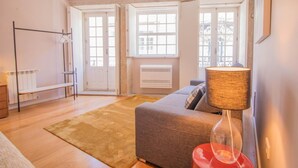 Una sala de estar moderna con un sofá gris, una lámpara roja y suelo de madera.