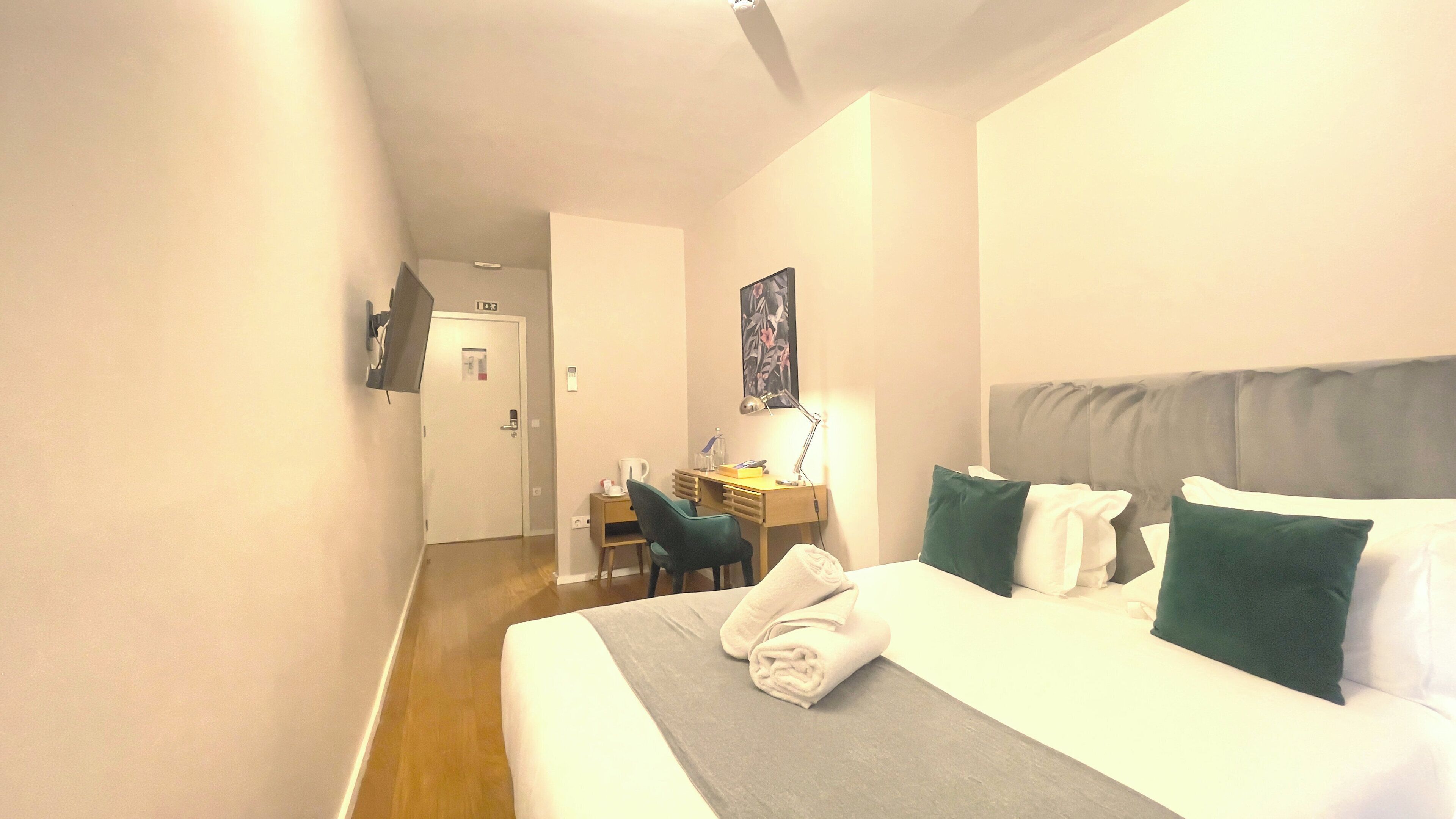 A hotel room with a bed, a desk, and a chair.