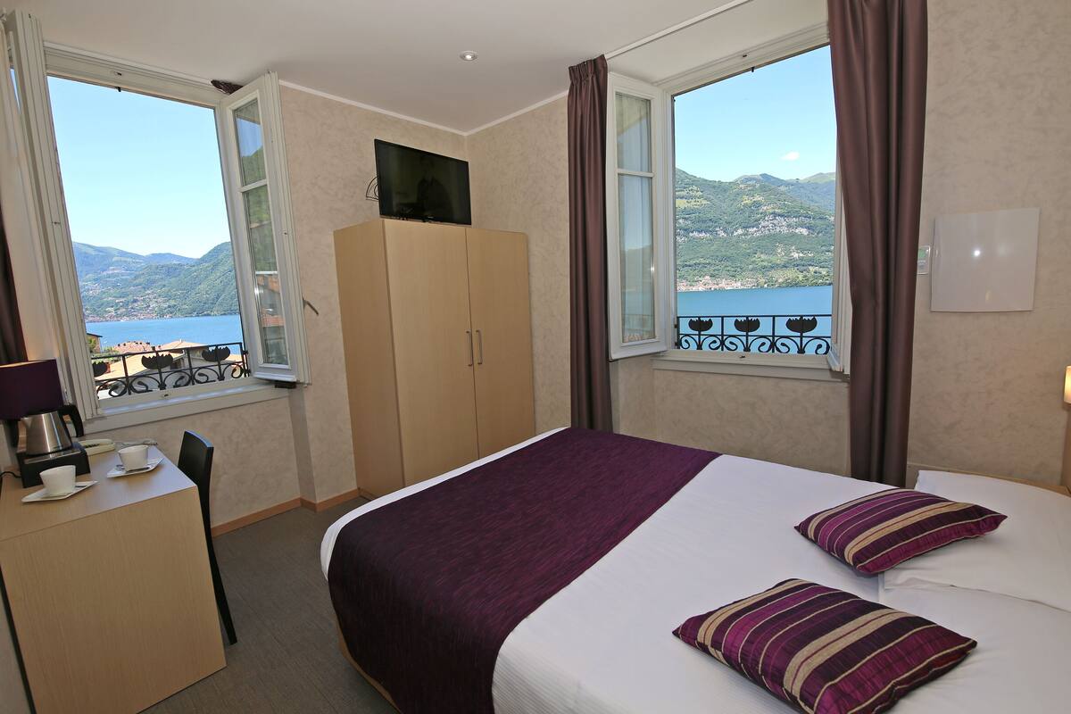 Habitación de hotel con cama, escritorio, televisor y vista al mar.