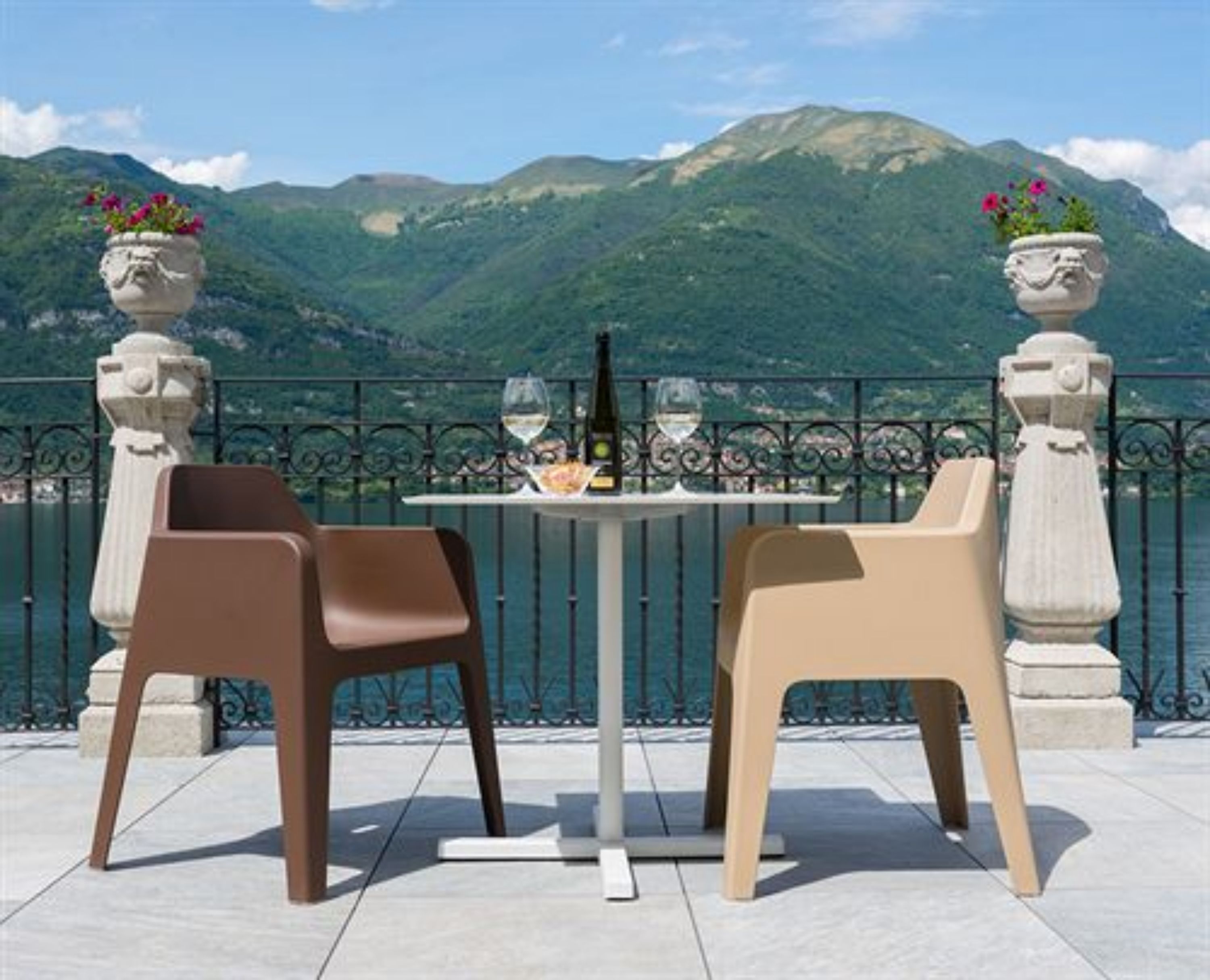 Une terrasse avec deux chaises et une table, d’où l’on peut admirer un paysage montagneux.
