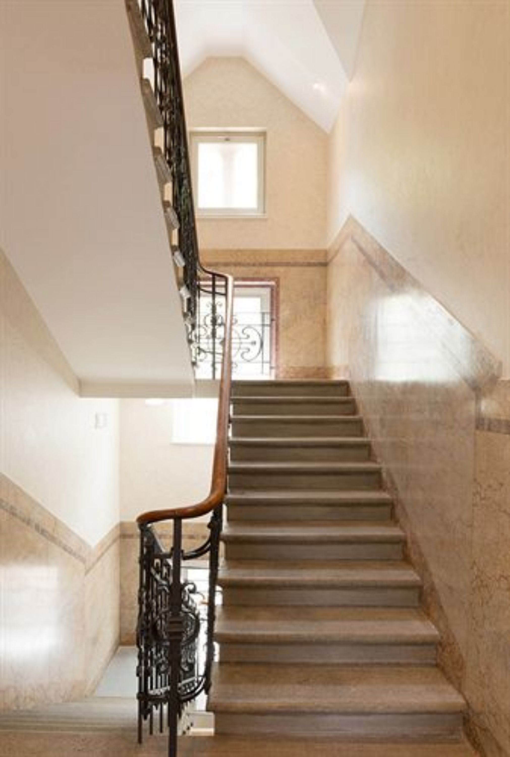 A staircase with a handrail and a window at the top.