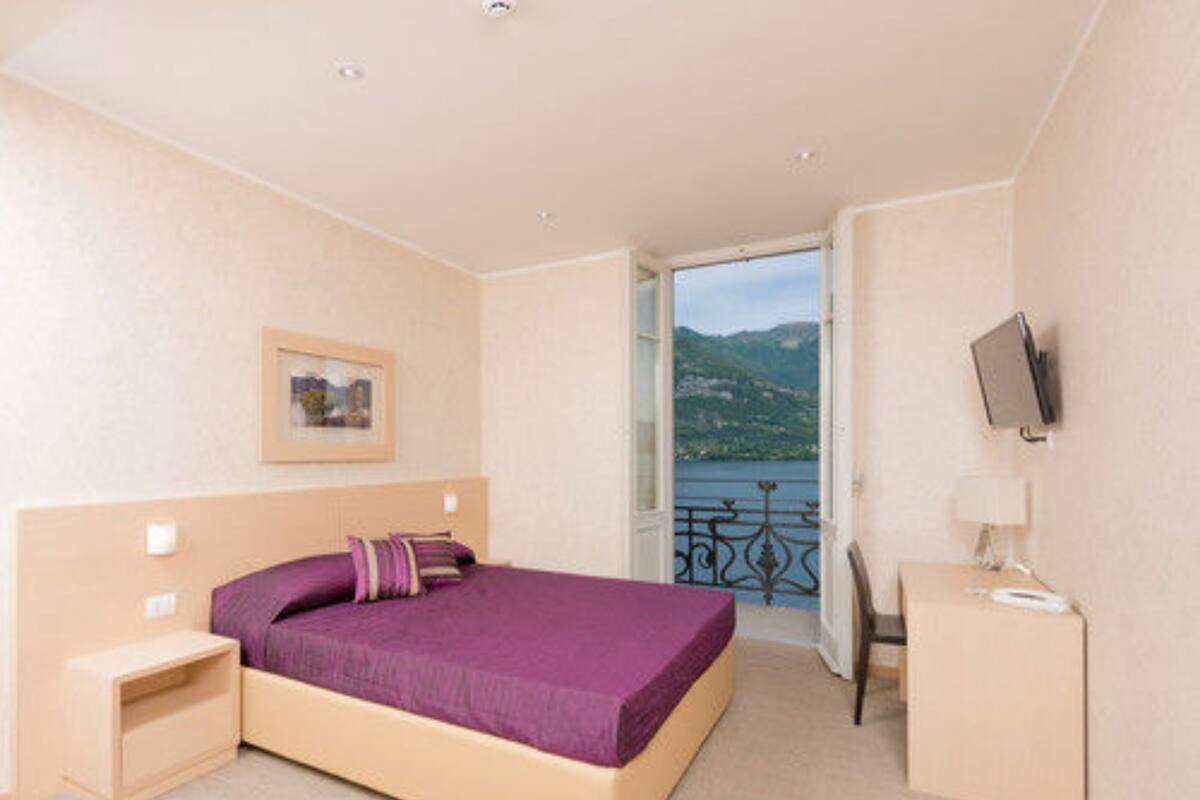 Un dormitorio con cama, escritorio, televisor y vista a un lago.
