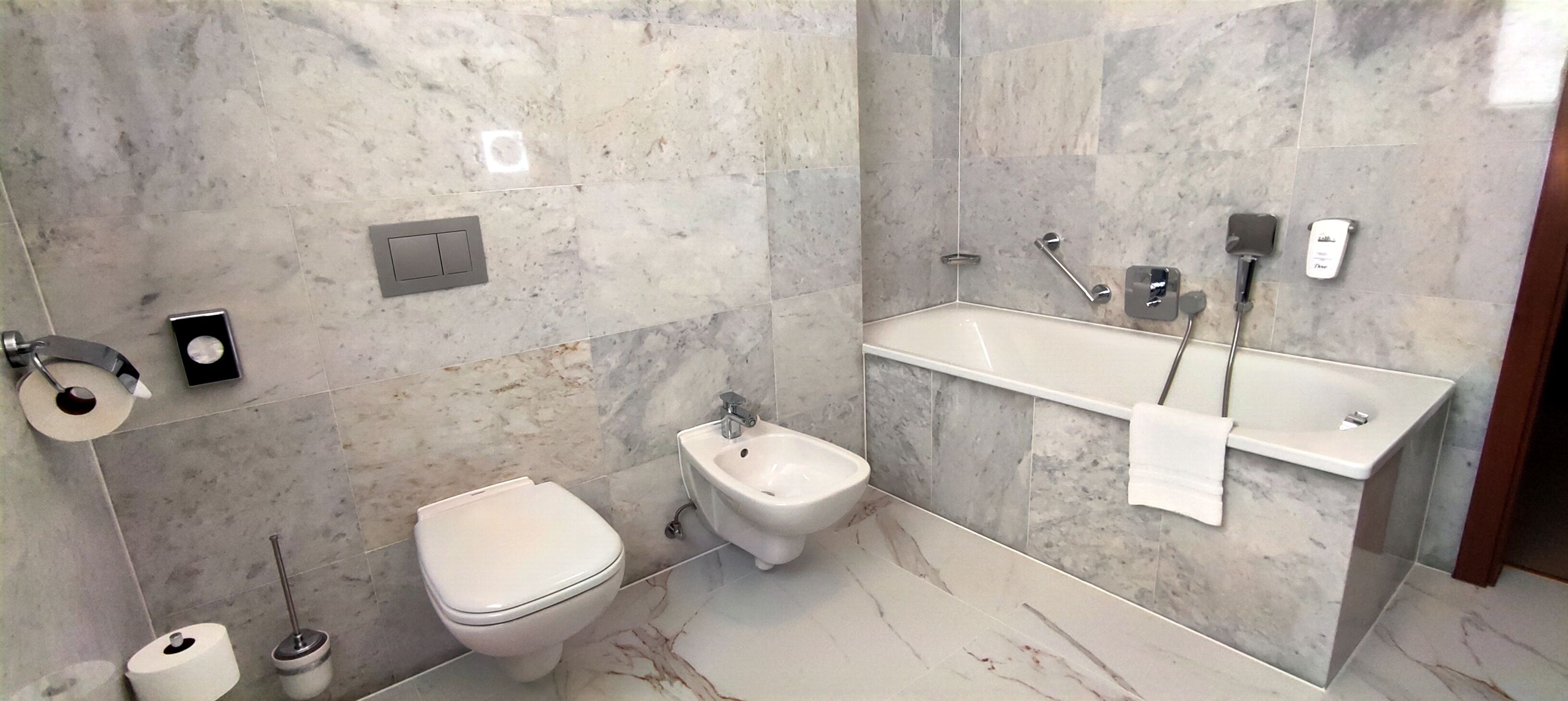 A modern bathroom with a toilet, bidet, and a large bathtub.