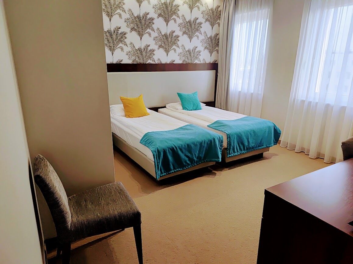 A hotel room with two beds, a desk, and a chair.