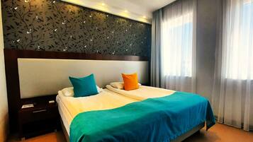 A hotel room with a large bed, two pillows, a nightstand, and a decorative wall panel.
