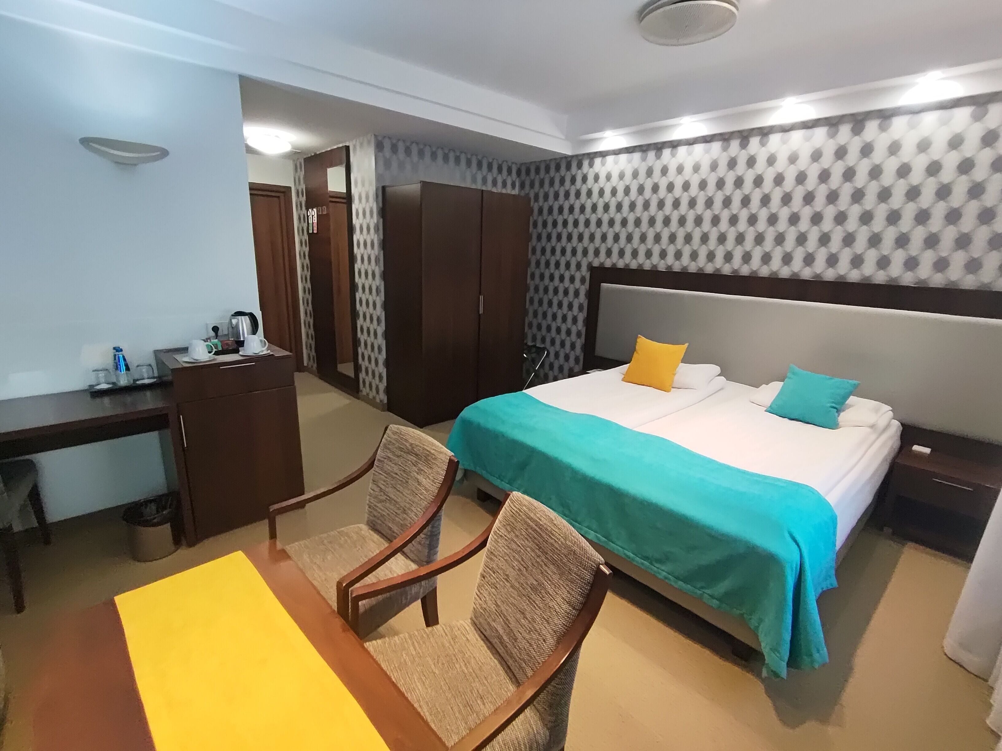 Una habitación de hotel con una cama, un escritorio, una silla, un armario y una mesita de noche.
