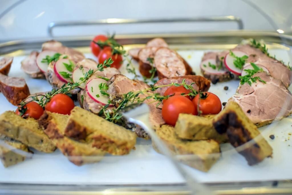 A tray of sliced meat with herbs and tomatoes.