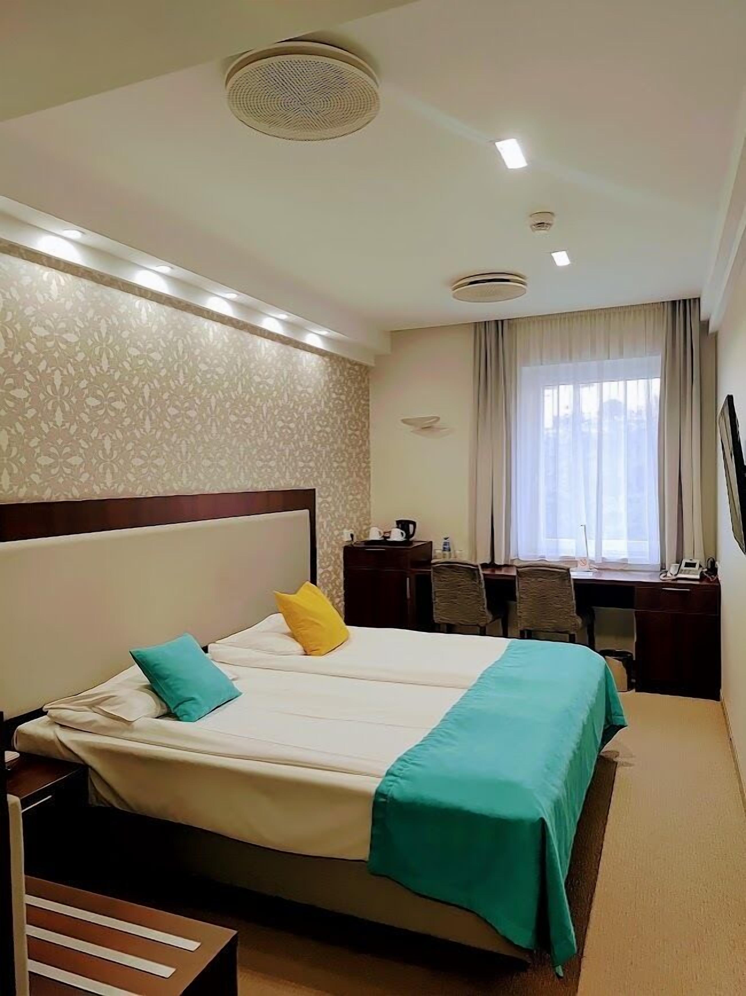 A hotel room with a large bed, a desk, and a chair.