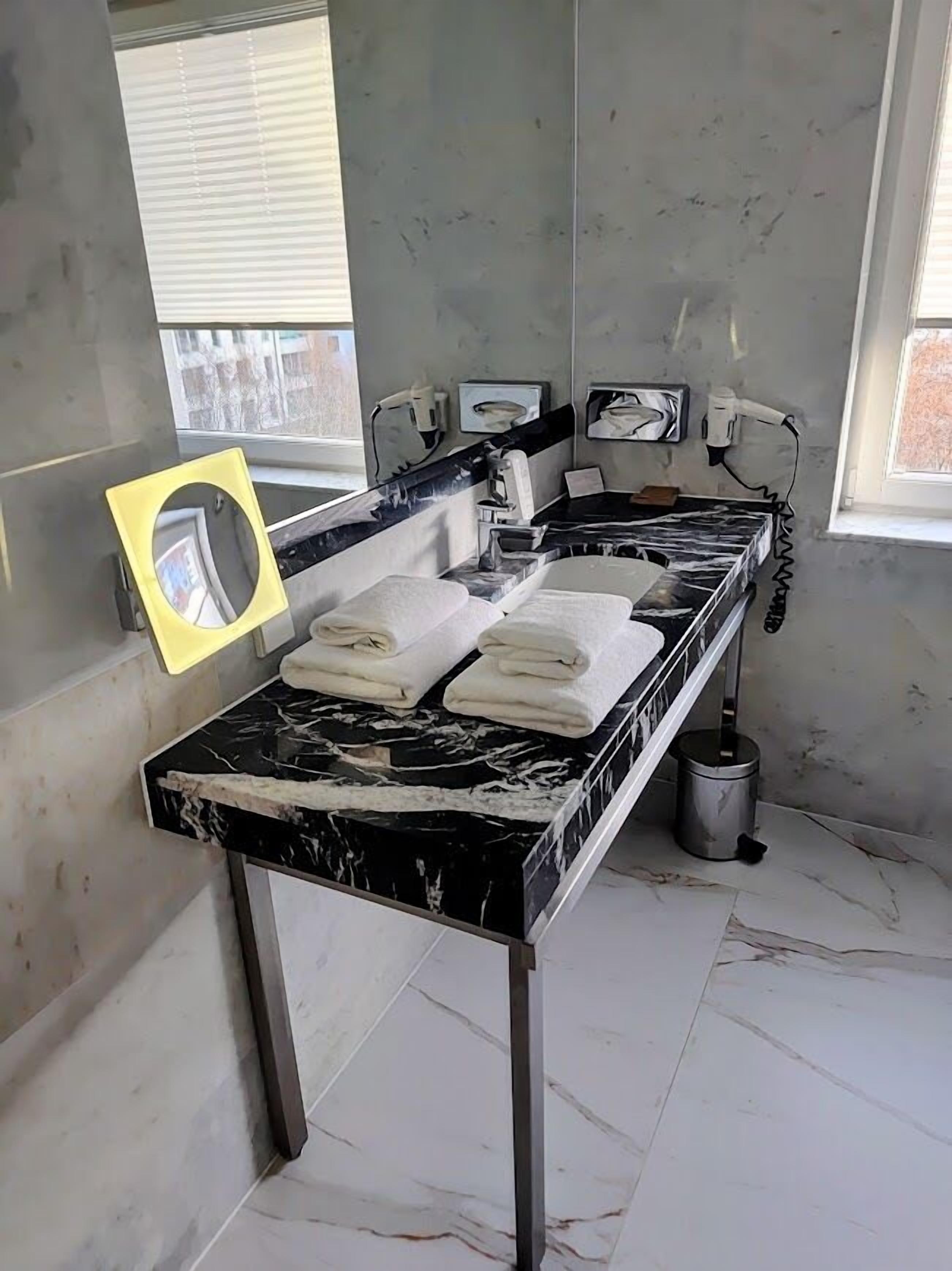 Un baño con encimera de mármol, dos lavamanos y toallas.