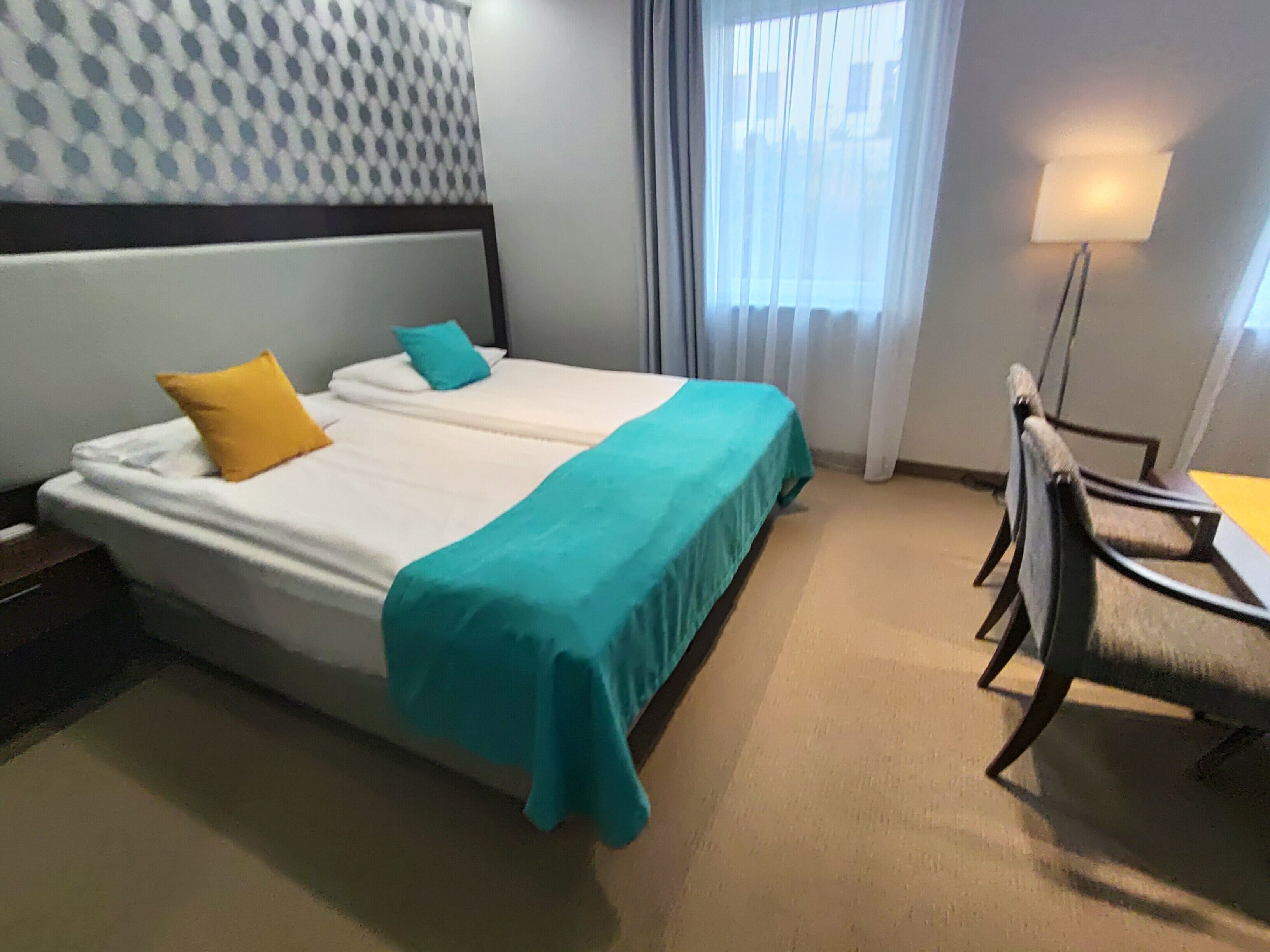 Une chambre d’hôtel avec deux lits, un bureau et une chaise.