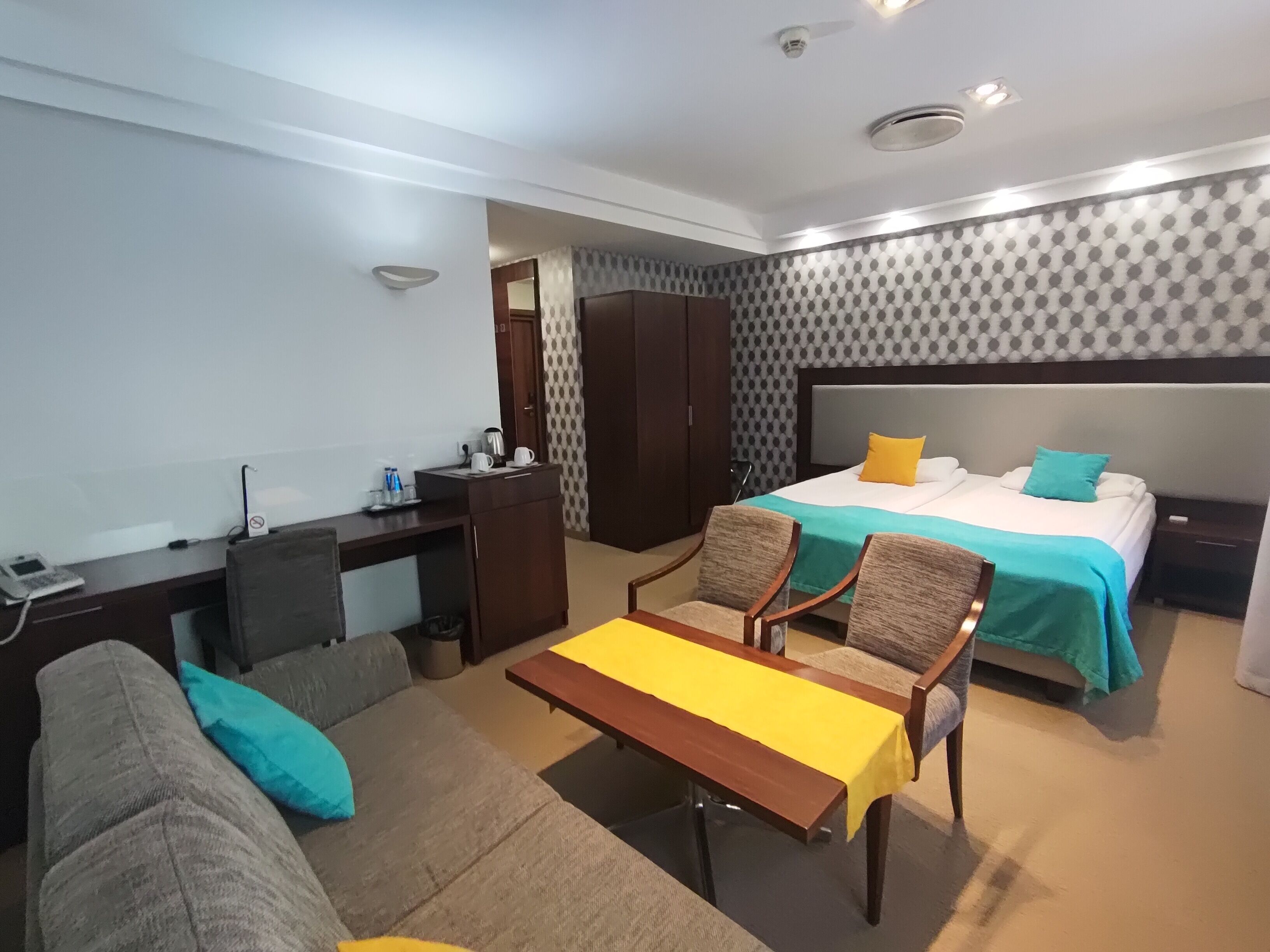 Une chambre d’hôtel avec un lit, un bureau, une chaise, un canapé et une petite table.