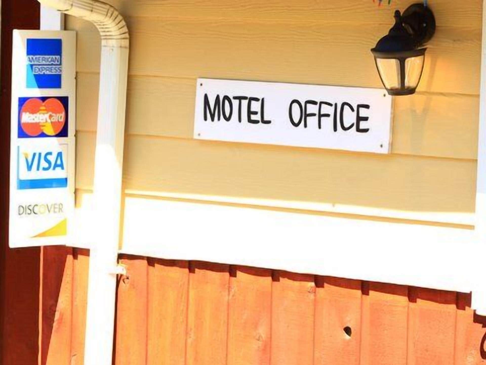 A motel office sign with a lamp above it.