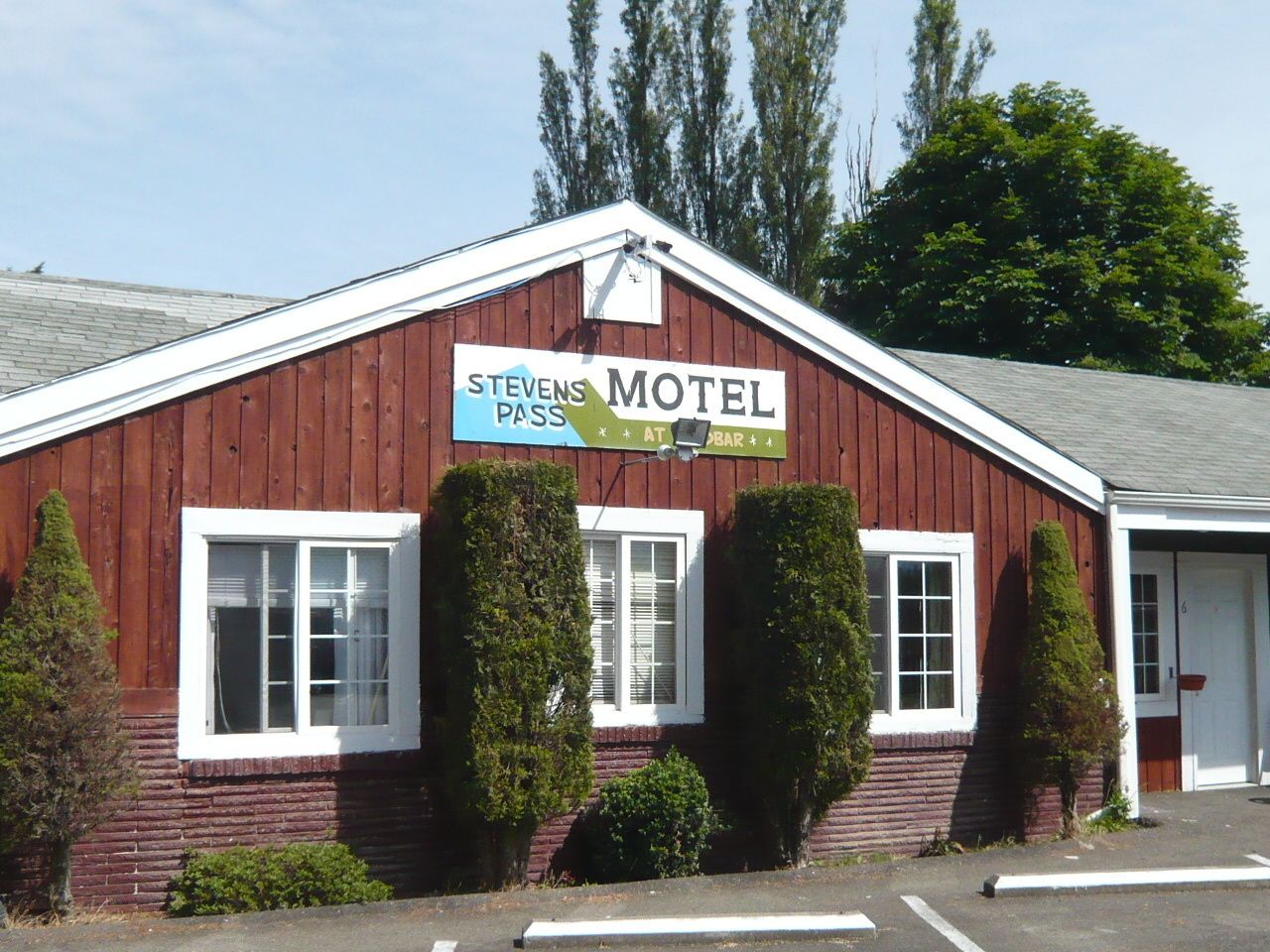 Um edifício de madeira vermelha com uma placa que diz "Stevens Motel" e "Apresente-se no Bar".