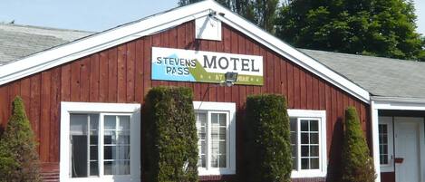 A red wooden building with a sign that reads "Stevens Motel" and "Pass at Bar."