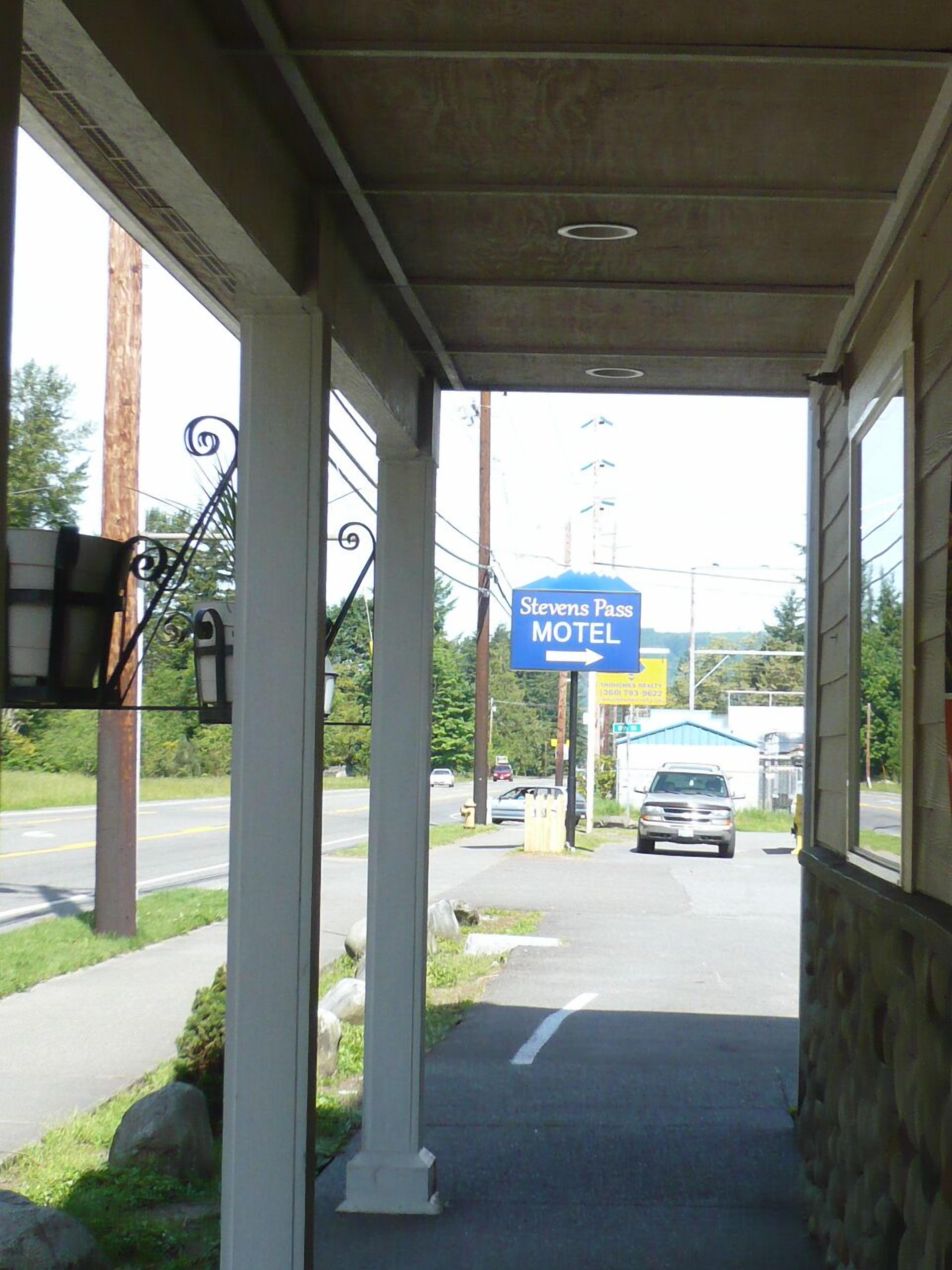 L’entrée d’un motel, avec un passage couvert, une enseigne indiquant « Stevens Pass Motel » et une route où circulent des véhicules.