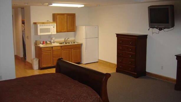 A compact room with a kitchenette, a bed, a dresser, and a television. - Stevens Pass Motel (Gold Bar)