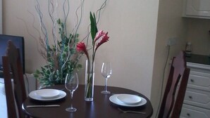 A dining table set with plates, wine glasses, and a vase with flowers. - Summers Inn (Gros Islet)