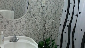 A bathroom with a white sink, a mirror, a decorative plant, and a shower curtain with a black and white pattern. - Summers Inn (Gros Islet)