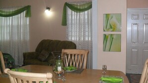 A dining area with a wooden table, chairs, and a vase with flowers. - Summers Inn (Gros Islet)