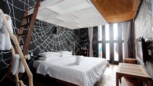 Un dormitorio con cama, una escalera de madera, un sillón colgante y un ventanal grande.