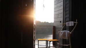 Una terraza de madera con una mesa y sillas, con vista a un cuerpo de agua.