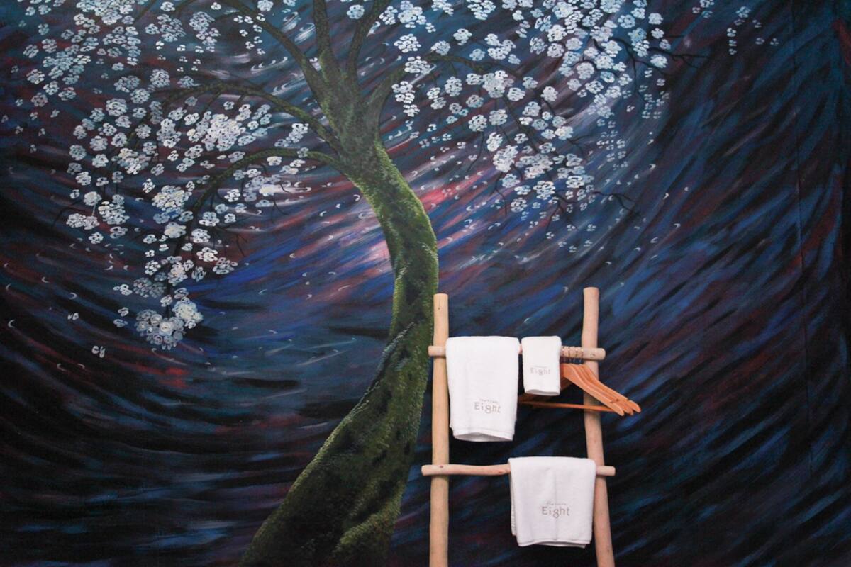 Un tableau représentant un arbre aux fleurs blanches et une échelle en bois sur laquelle sont suspendues des serviettes.