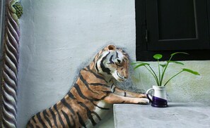 Una estatua de tigre junto a una pared blanca con una puerta negra.