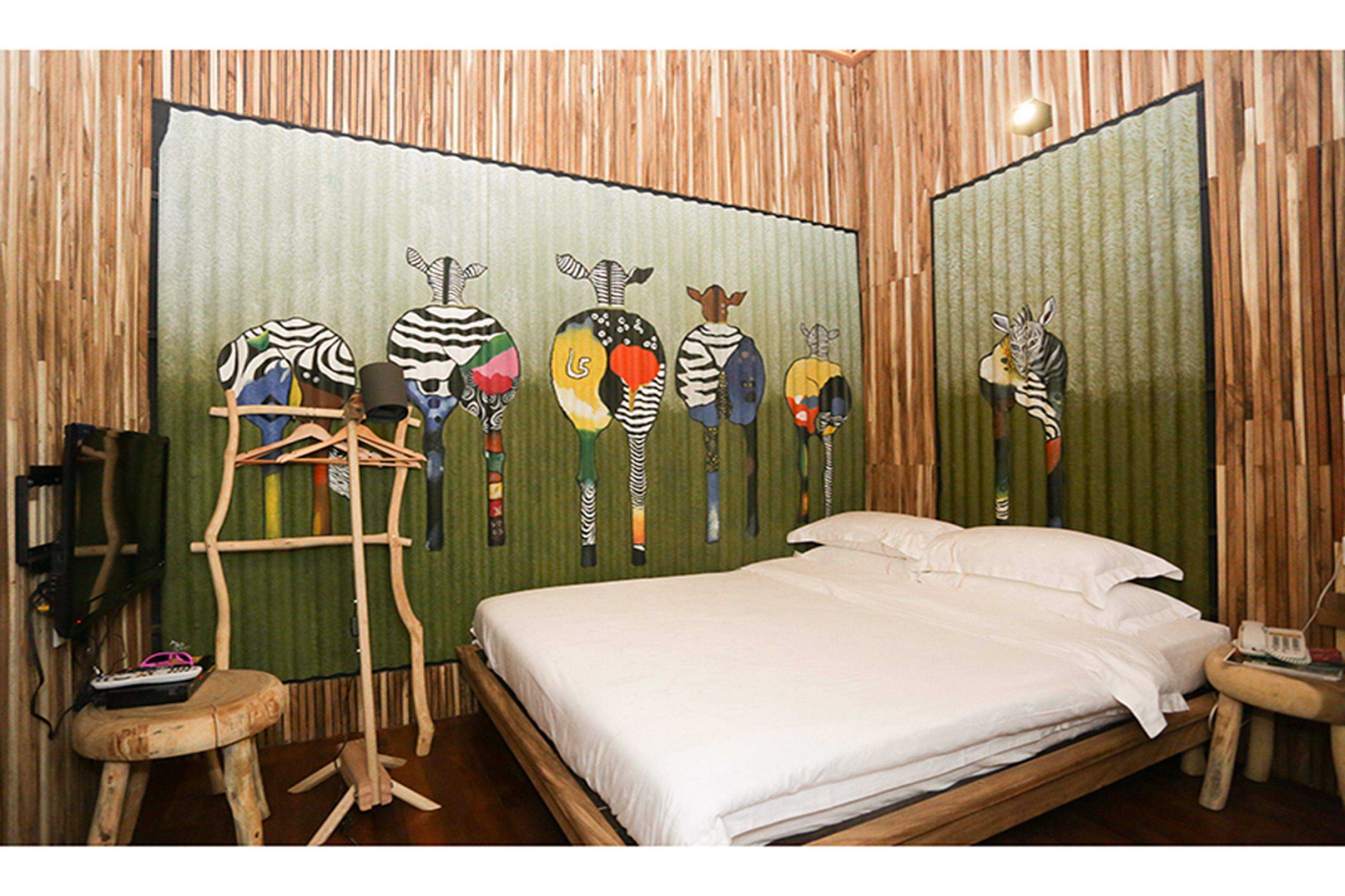 A room with a bed, a wooden ladder, and a wall with zebra paintings.