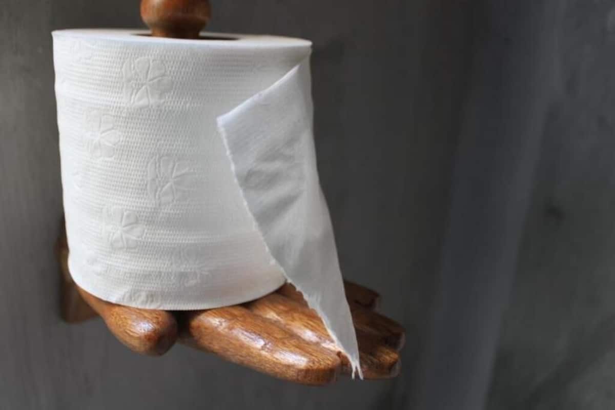A roll of toilet paper on a wooden stand.