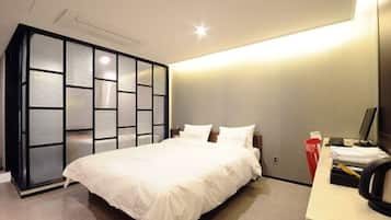 A modern bedroom with a large bed, a desk with a computer, and a sliding door closet.