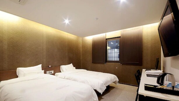 A hotel room with two beds, a desk with a computer, and a TV mounted on the wall. - Queens Hotel Seomyeon Busan (Busan)