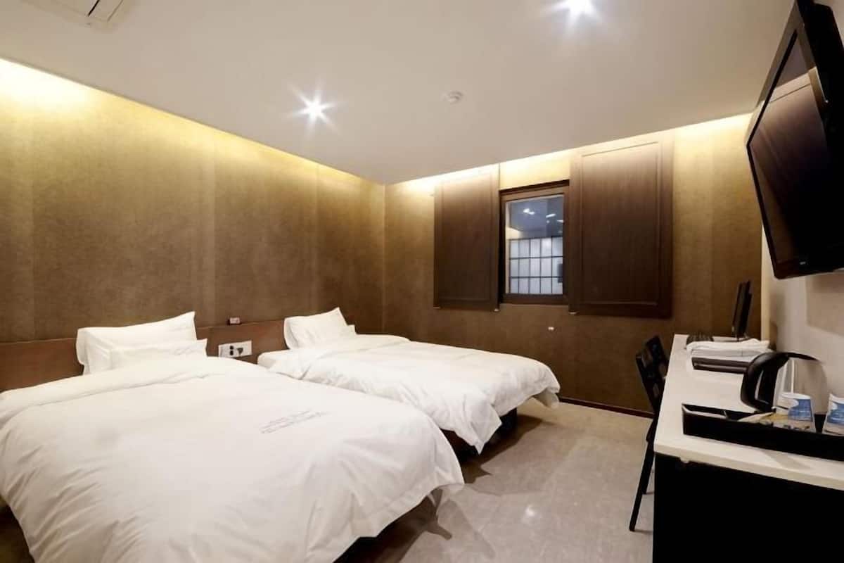 A hotel room with two beds, a desk with a computer, and a TV.