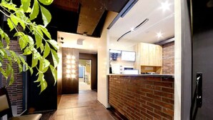 A modern interior with a brick wall, wooden floor, and a seating area with a chair. - Queens Hotel Seomyeon Busan (Busan)