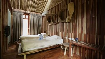A room with a bed, a wooden bench, and a wall with vertical wooden slats.