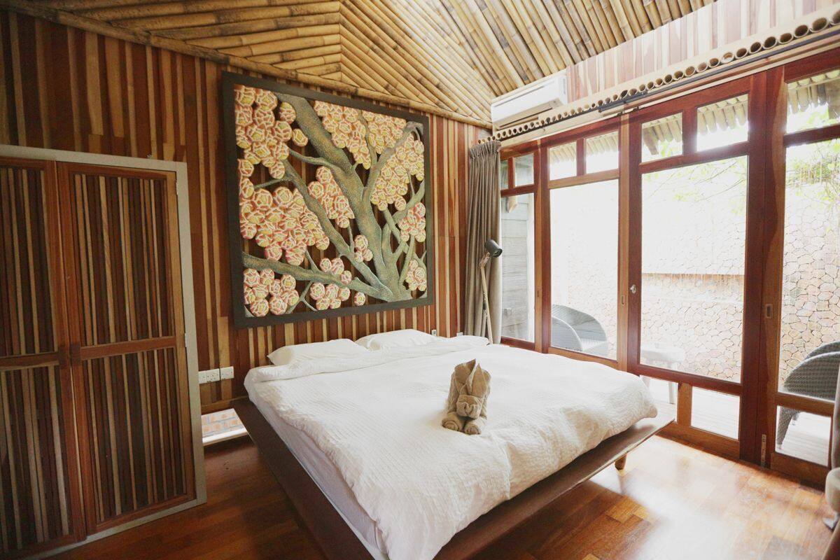 A room with a bed, a decorative wall panel, and large windows.