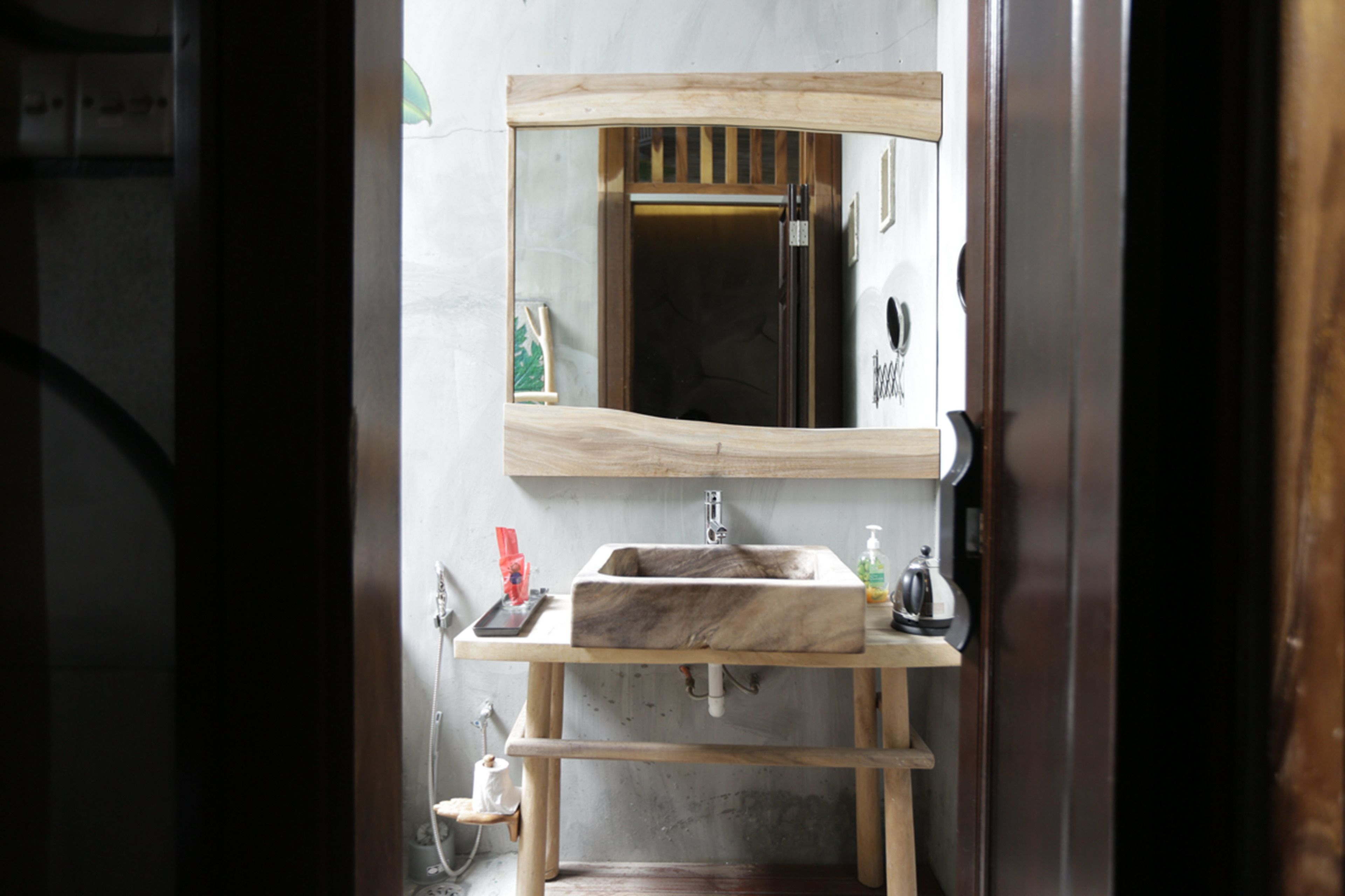 Une salle de bain avec un meuble-lavabo en bois, un lavabo en marbre et un miroir.