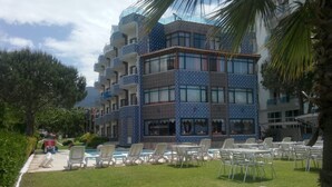 Un hotel con varios balcones, mobiliario exterior y una zona de piscina.