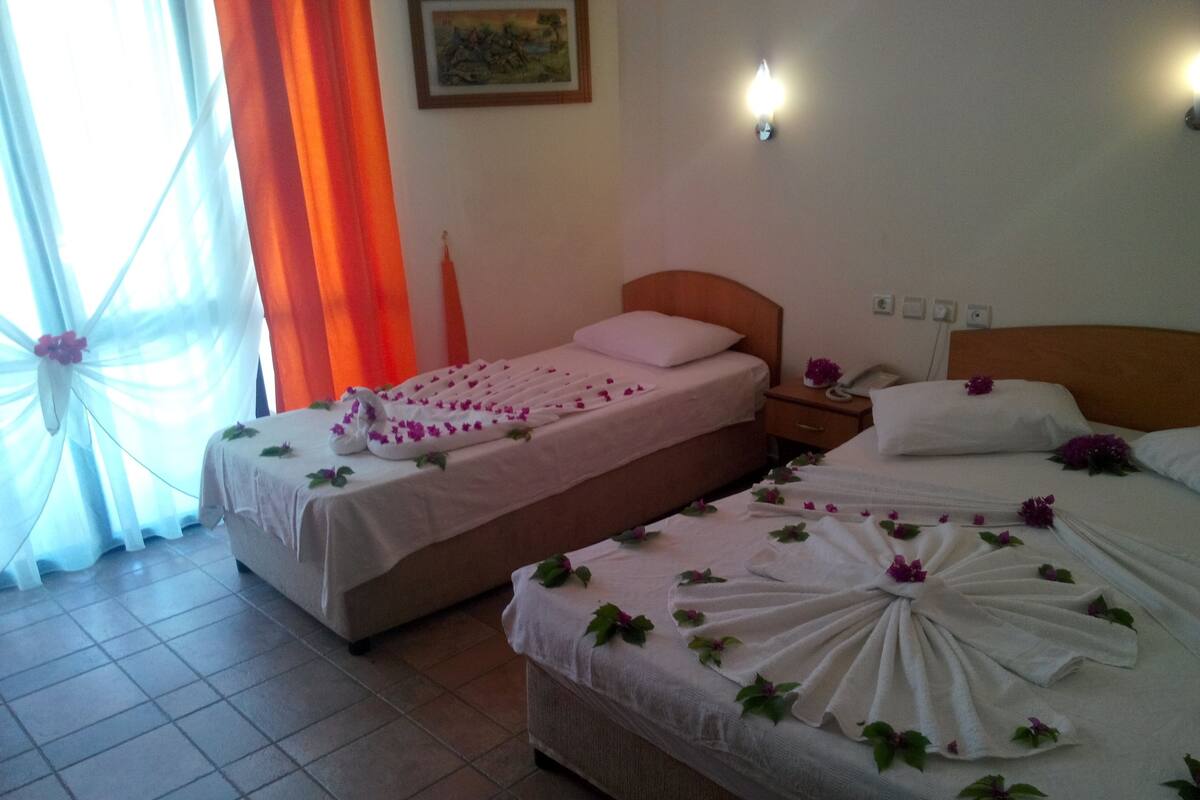 A hotel room with two beds, each adorned with white linens and floral arrangements.