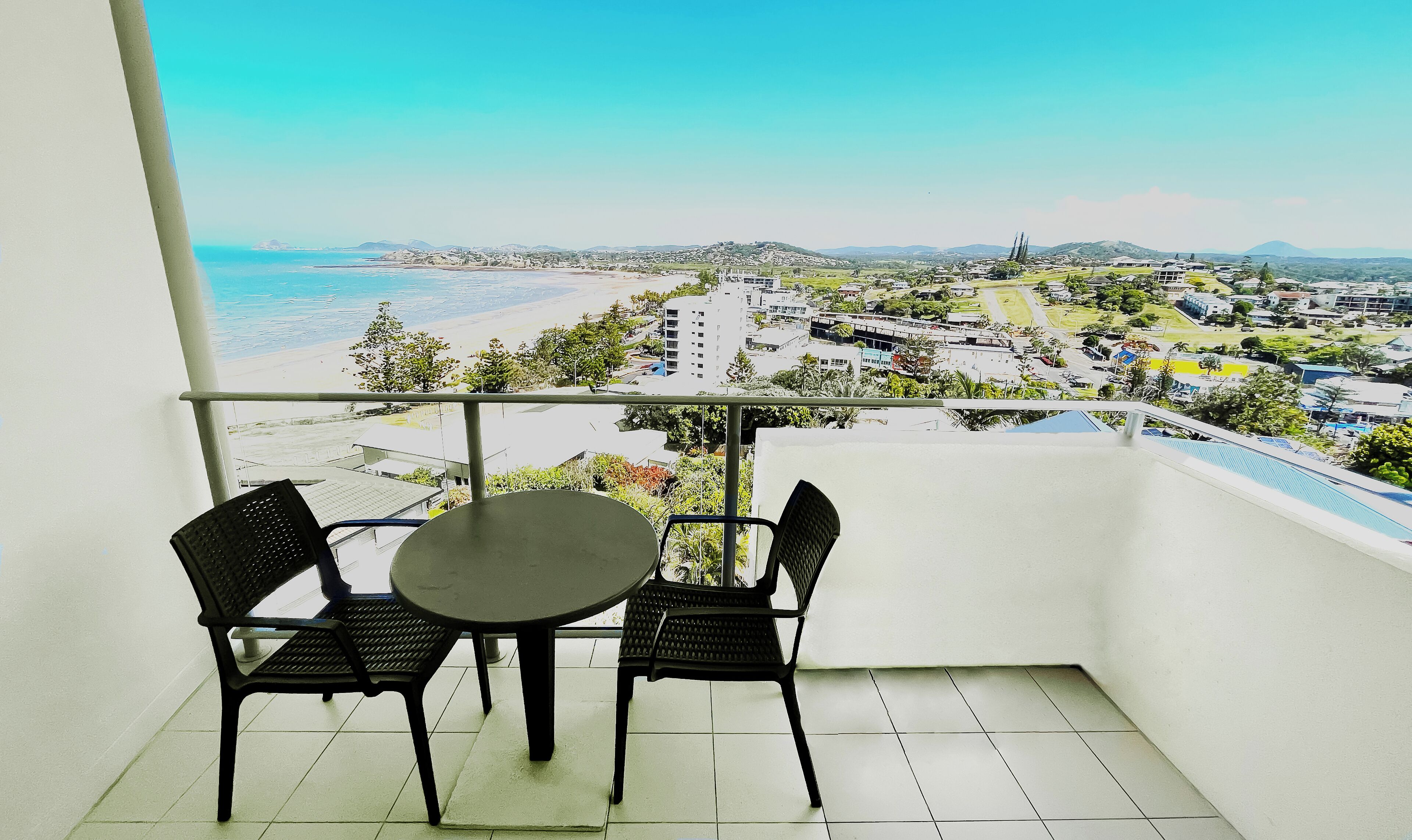 Un balcon avec une table et des chaises, donnant sur une plage et offrant une vue sur la ville.