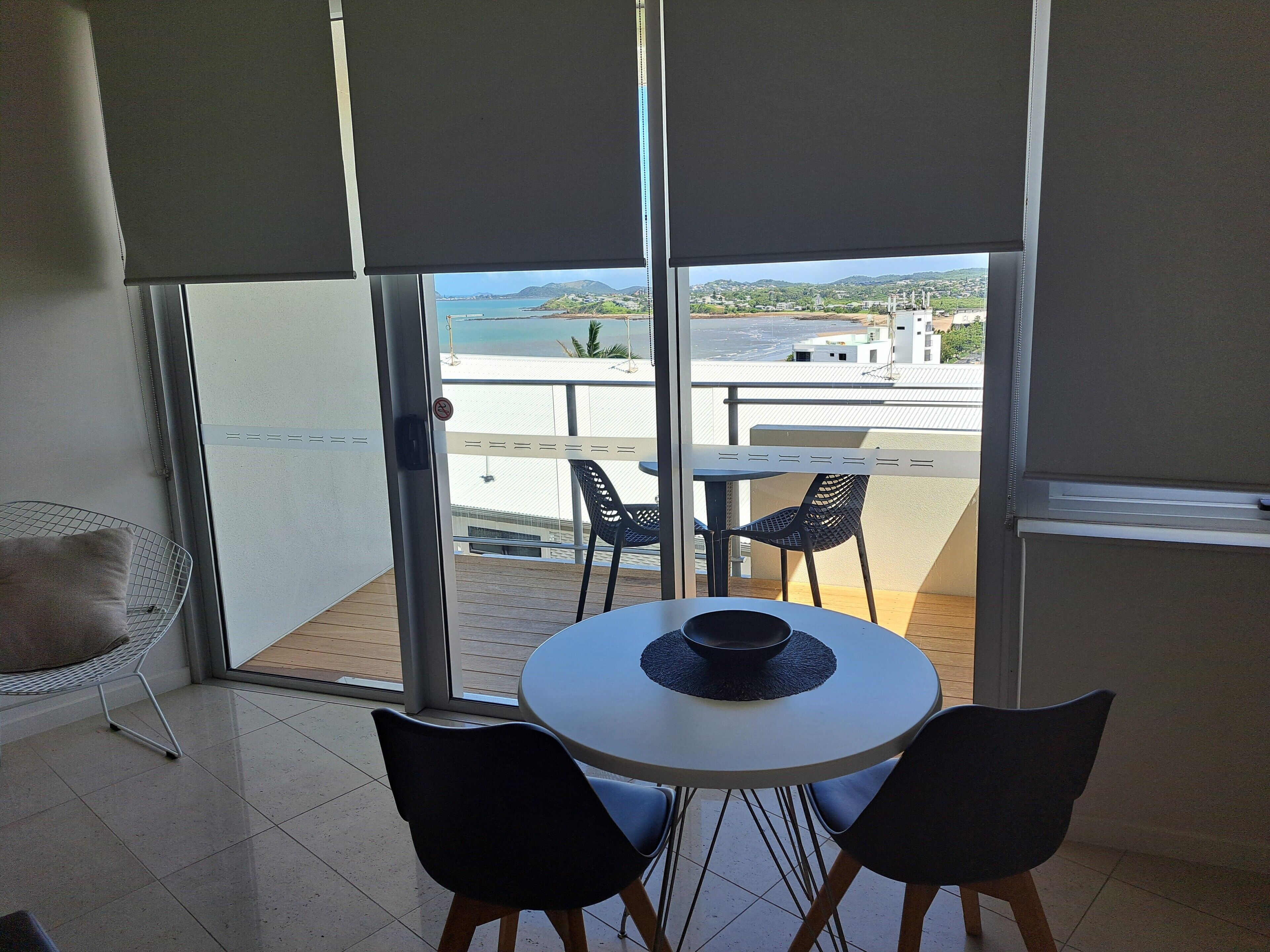 Un balcone con tavolo e sedie, vista sul mare e sullo skyline urbano.