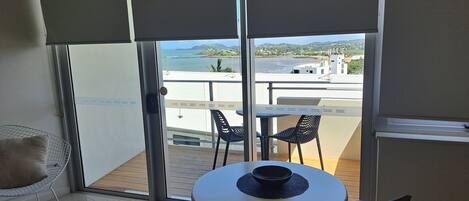 Un balcone con tavolo e sedie, vista sul mare e sullo skyline urbano.